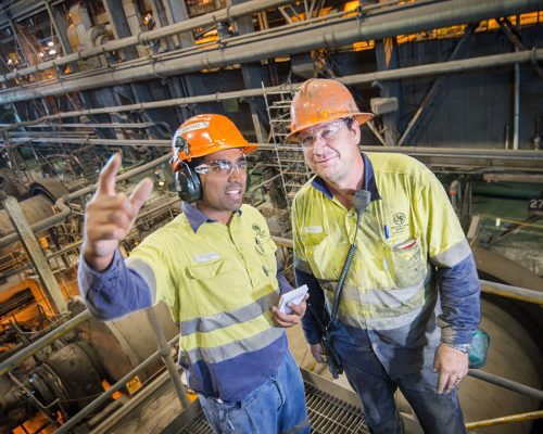 Melwyn Jerome, Safety Advisor, and Todd Allen, Operator (WorkPak) discuss workplace safety at the Zinc Lead Concentrator at Glencore's Mount Isa Mines. The photographer is Rob Parsons of Through The Looking Glass Studio. The image orientation is landscape.